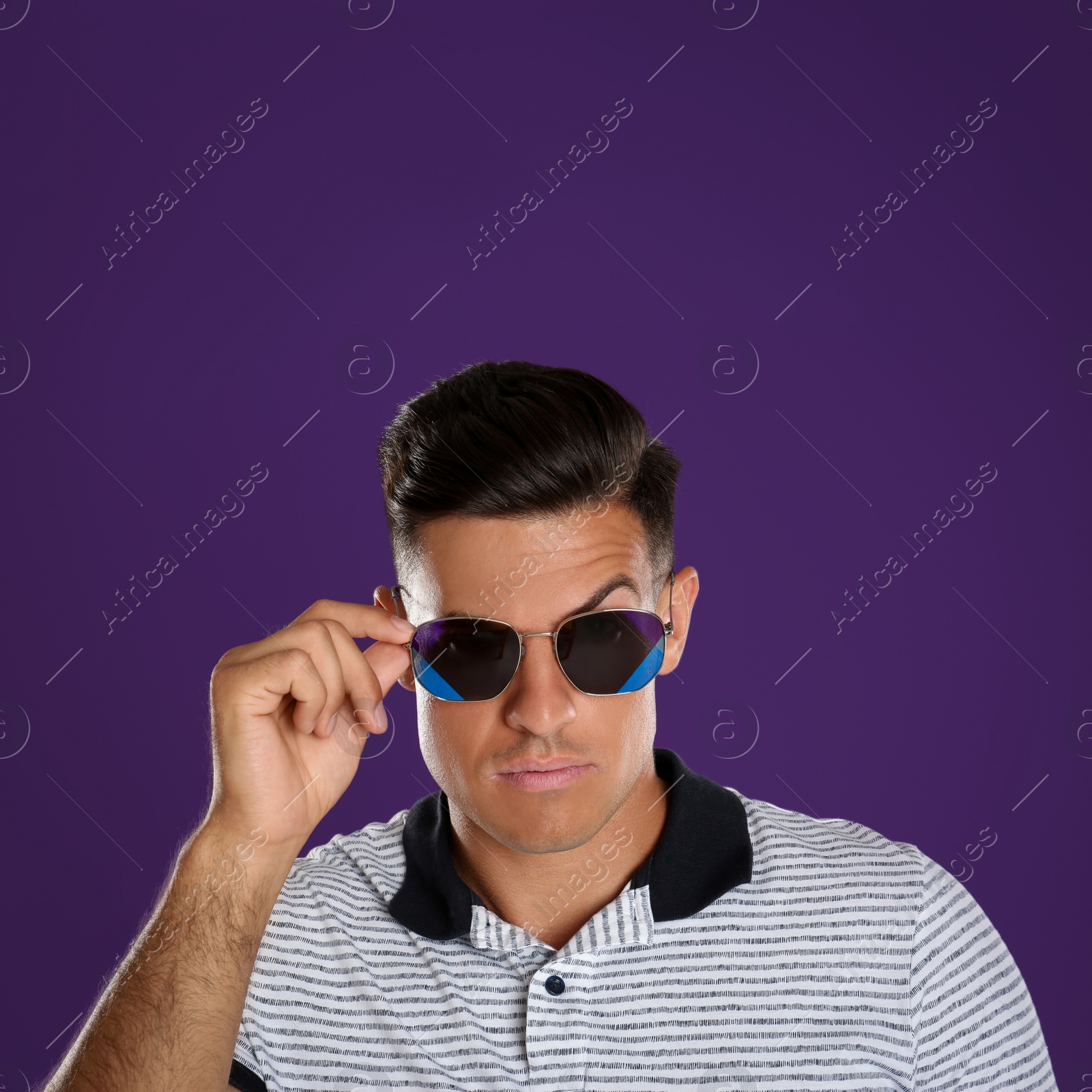 Photo of Handsome man wearing sunglasses on purple background