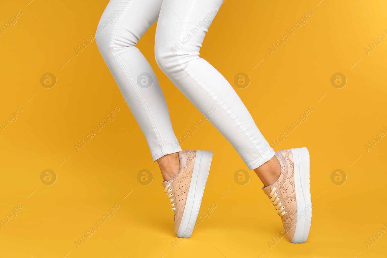 Photo of Woman wearing stylish shoes on yellow background, closeup