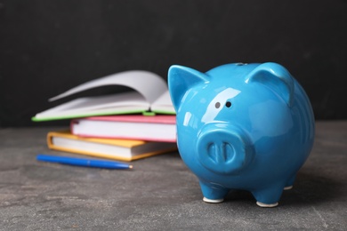 Photo of Piggy bank with stack of books on table