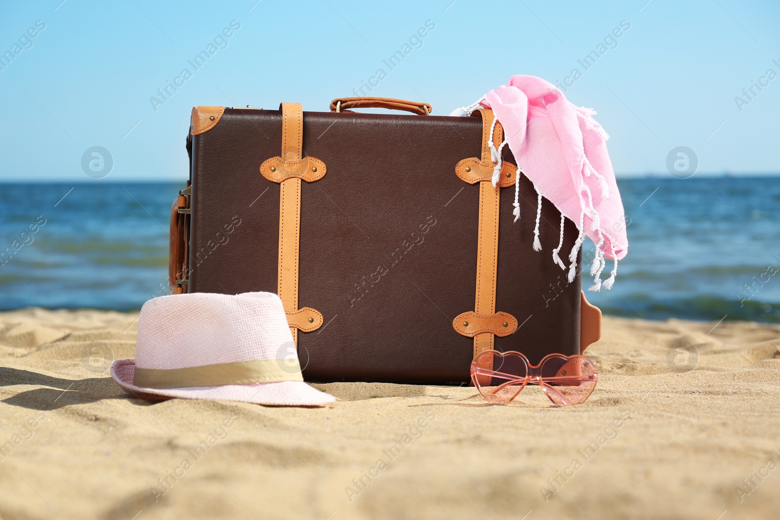 Photo of Suitcase and beach accessories on sand near sea