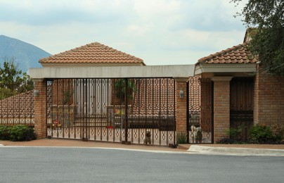 Closed metal gates near beautiful house on city street