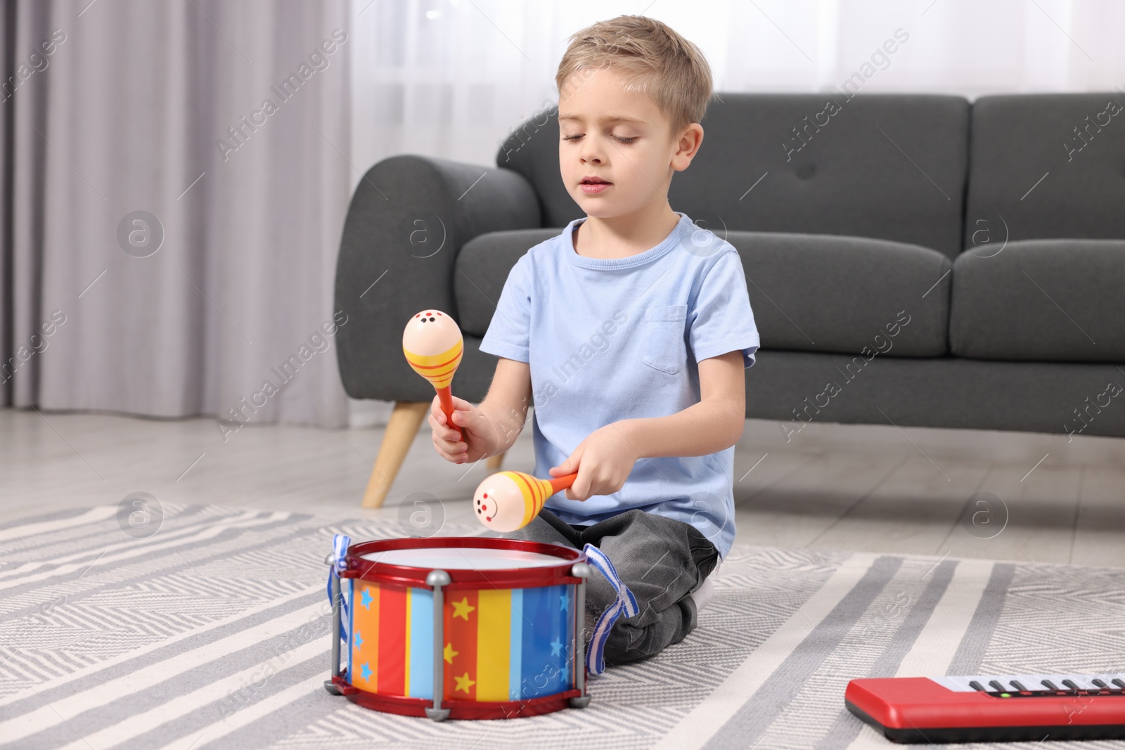 Photo of Little boy playing toy maracas at home