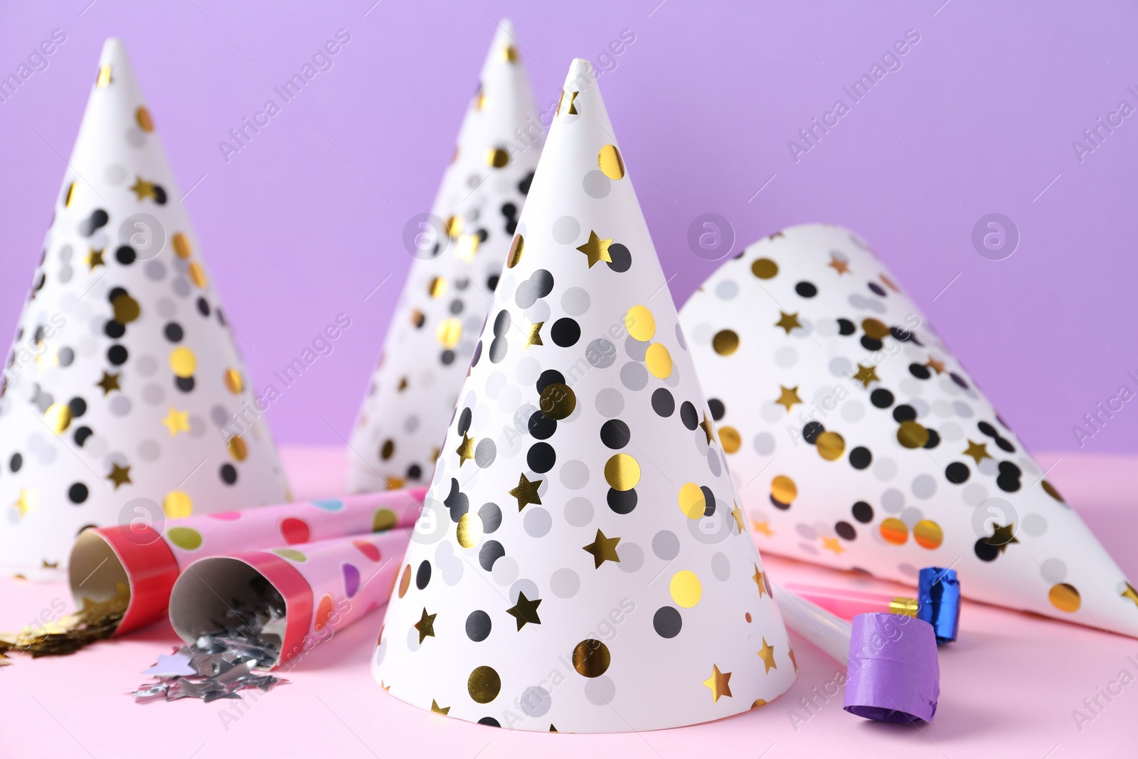 Photo of Party hats, confetti and blowers on color background