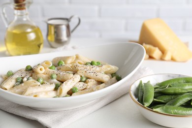 Photo of Delicious pasta with green peas and creamy sauce on white table