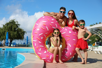 Photo of Happy family with inflatable ring near swimming pool.  Summer vacation