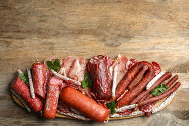 Photo of Different types of sausages with parsley on wooden table, top view. Space for text