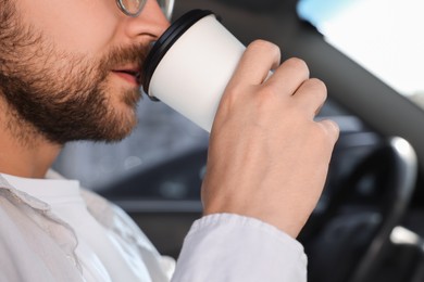 Photo of To-go drink. Man drinking coffee in car, closeup