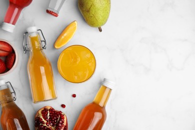 Photo of Tasty kombucha in bottles, glass and fresh fruits on white marble table, flat lay. Space for text