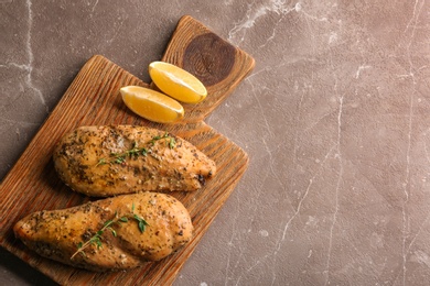 Photo of Baked lemon chicken with thyme served on grey marble table, top view. Space for text
