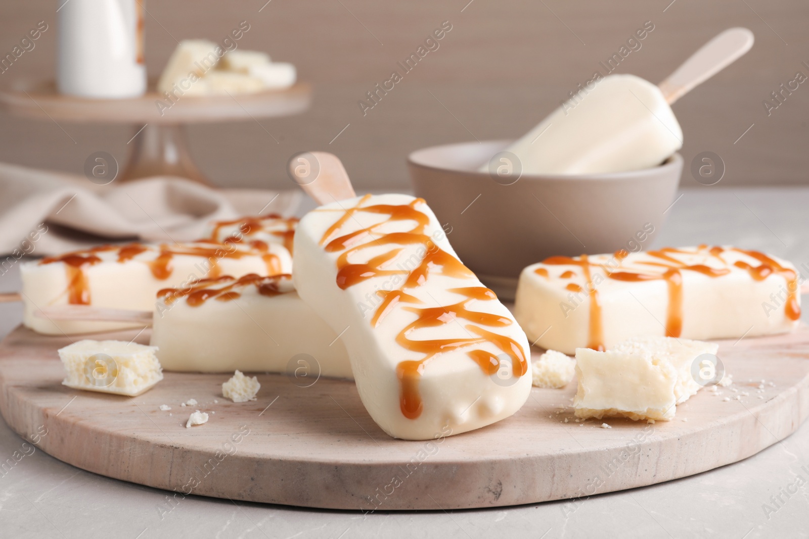 Photo of Delicious glazed ice cream bars and chocolate on light grey marble table