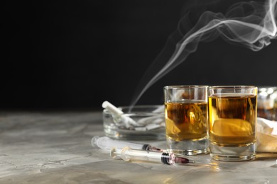 Photo of Alcohol and drug addiction. Whiskey in glasses and syringes on grey background, space for text