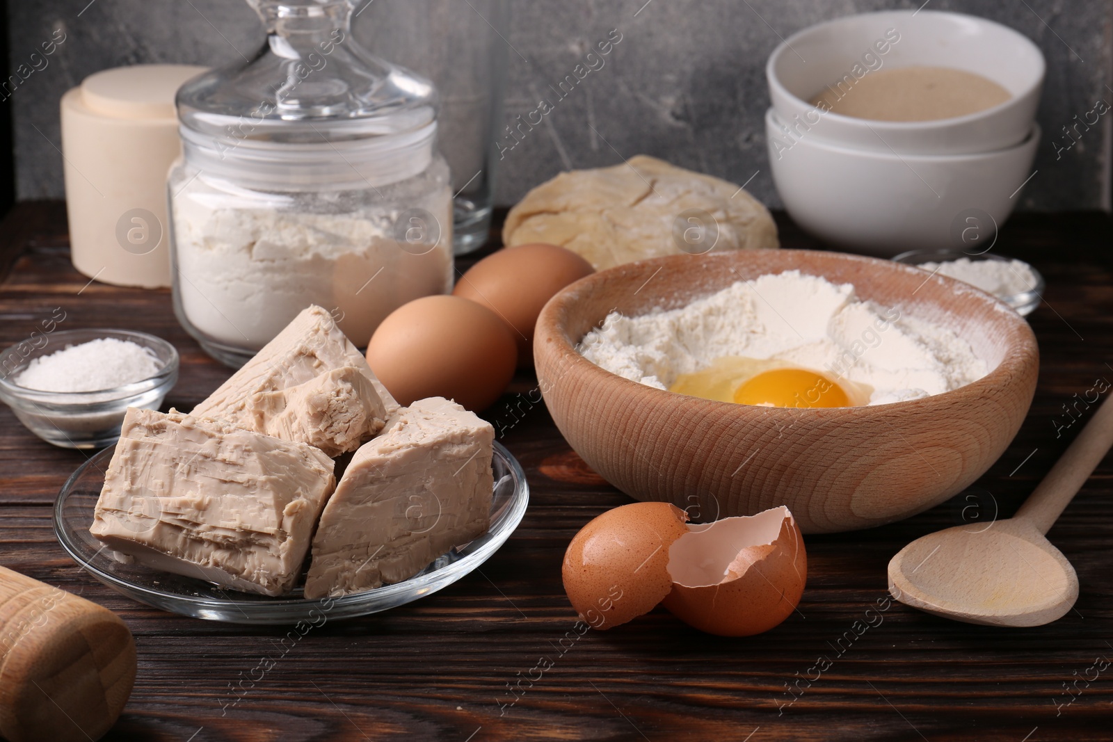 Photo of Compressed yeast, eggs, salt, dough and flour on wooden table