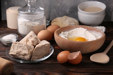 Compressed yeast, eggs, salt, dough and flour on wooden table