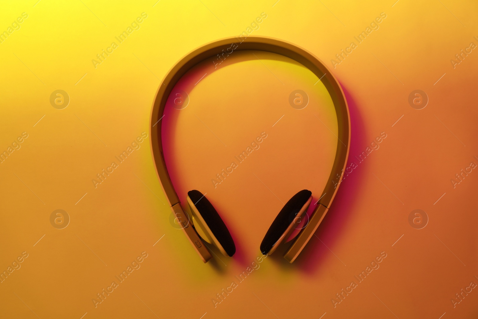 Photo of Stylish modern headphones with earmuffs on color background, top view