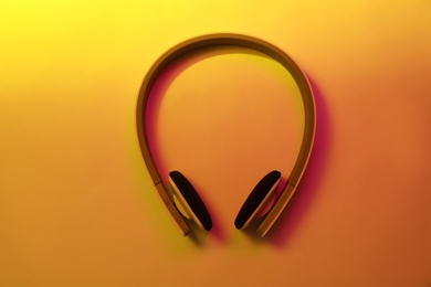 Stylish modern headphones with earmuffs on color background, top view