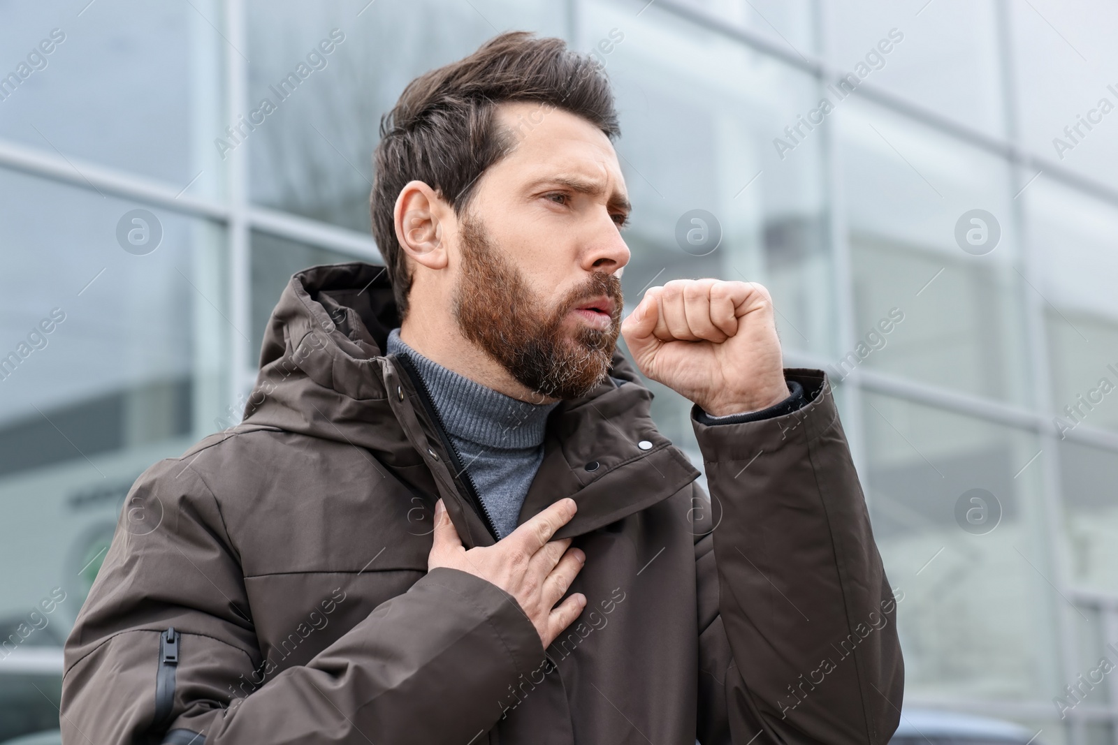 Photo of Sick man coughing on city street. Cold symptoms