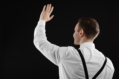 Man greeting someone on black background, back view