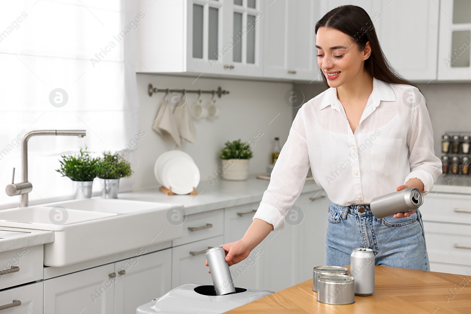 Photo of Smiling woman separating garbage in kitchen. Space for text