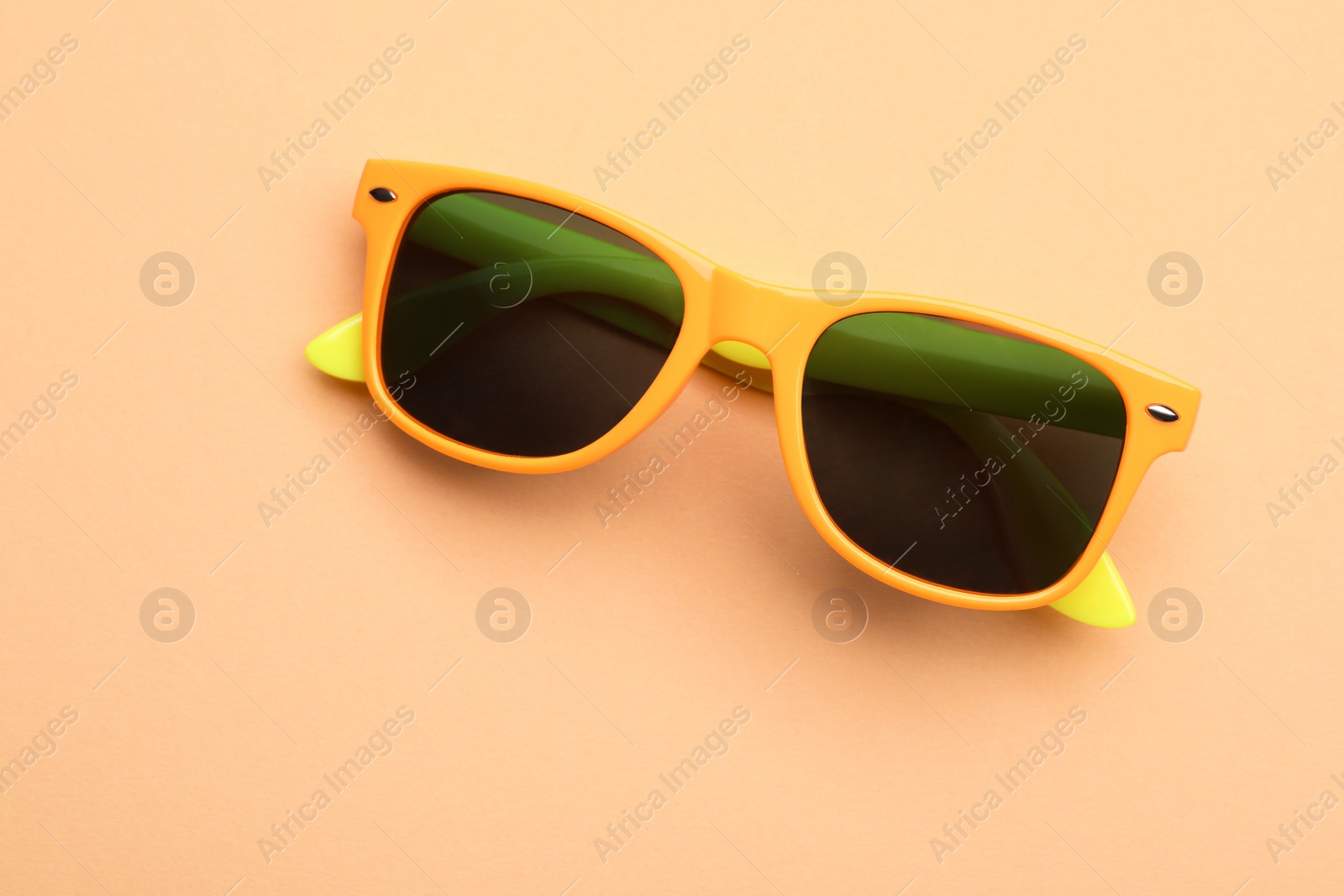 Photo of New stylish elegant sunglasses on beige background, top view