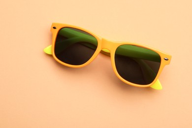 Photo of New stylish elegant sunglasses on beige background, top view