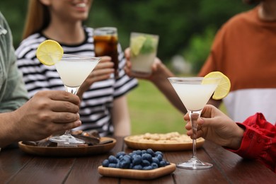 Photo of Friends with glasses of cocktails at table outdoors, closeup
