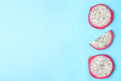 Slices of delicious ripe dragon fruit (pitahaya) on light blue background, flat lay. Space for text