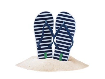 Photo of Striped flip flops in sand on white background