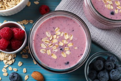Tasty berry smoothie with oatmeal on light blue wooden table, flat lay