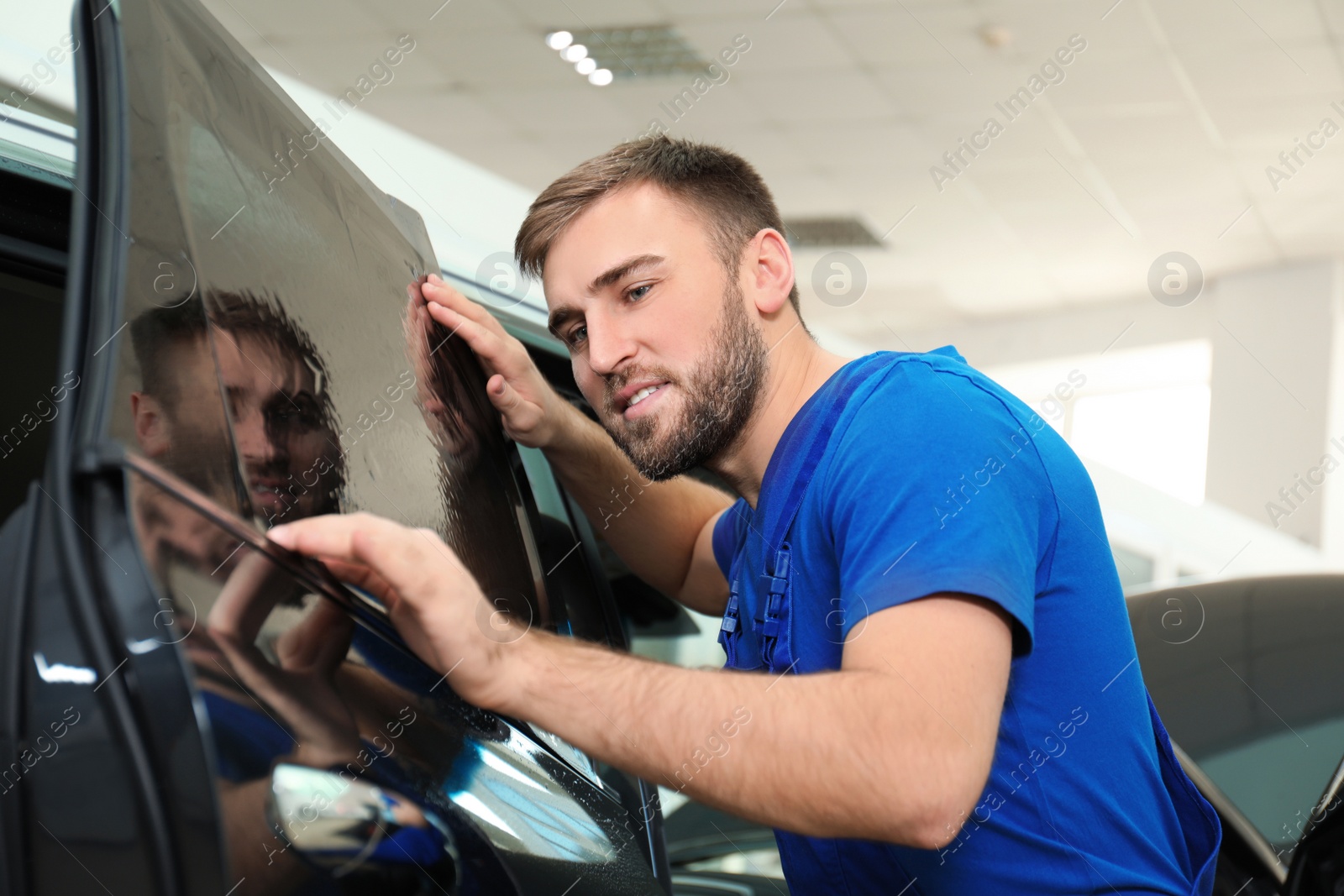 Photo of Worker tinting car window with foil in workshop