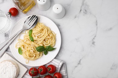 Photo of Delicious pasta with brie cheese and basil leaves served on marble table, flat lay. Space for text