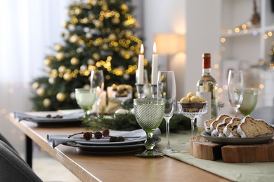 Christmas table setting with festive decor and dishware in room