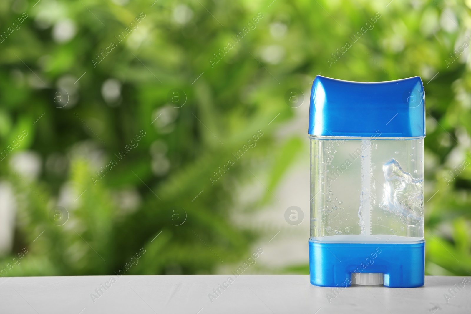 Photo of Deodorant container on white wooden table against blurred background. Space for text