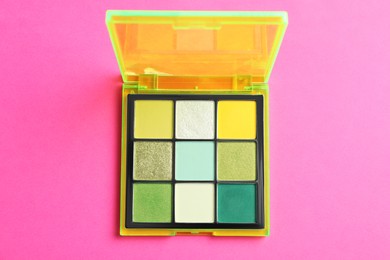 Photo of Colorful eyeshadow palette on pink background, top view