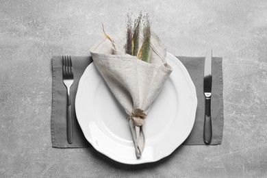 Photo of Plates with fabric napkin, decorative ring and cutlery on gray background, flat lay