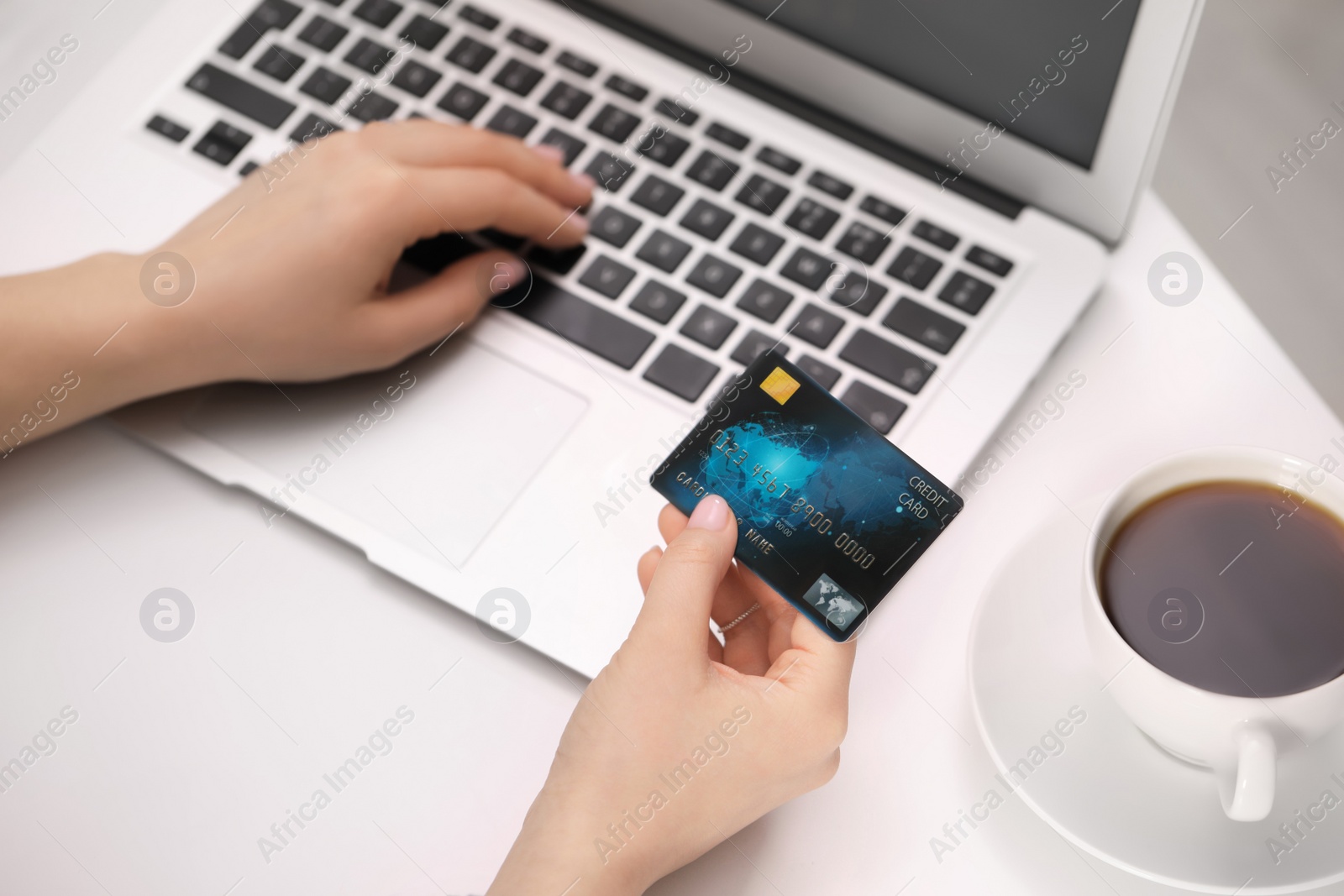 Photo of Woman with credit card using laptop for online shopping at white table, closeup