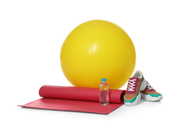 Photo of Fitness ball, yoga mat, bottle of water and sneakers isolated on white