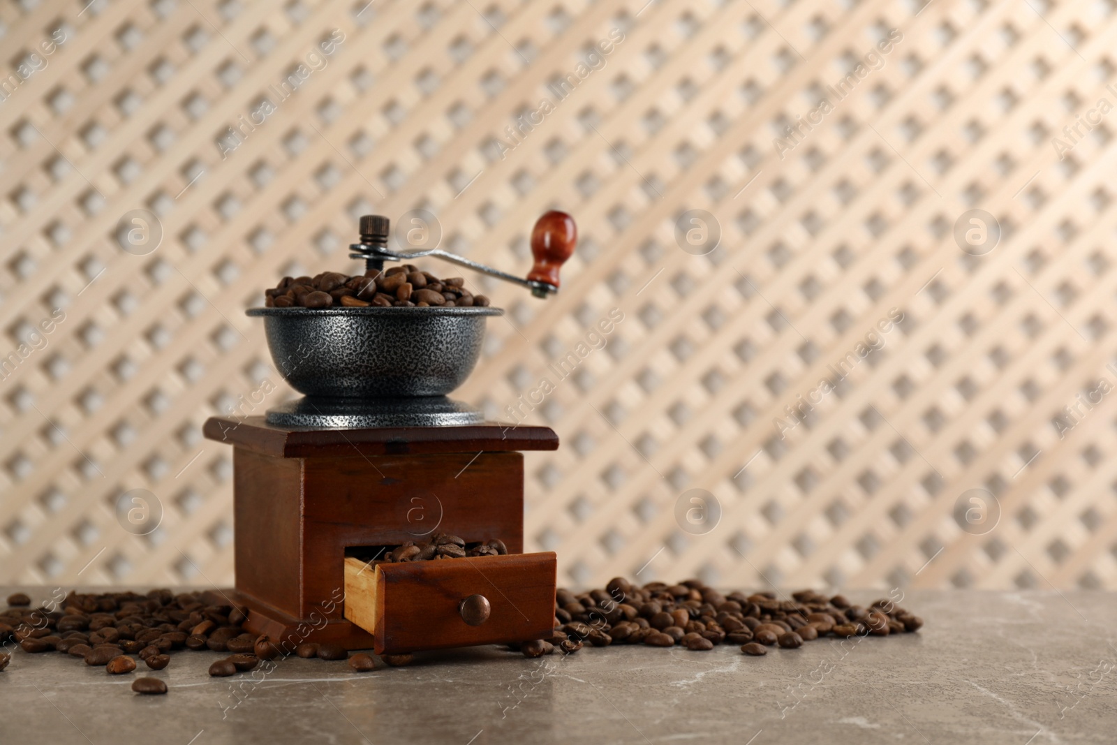 Photo of Vintage manual coffee grinder and beans on grey table. Space for text
