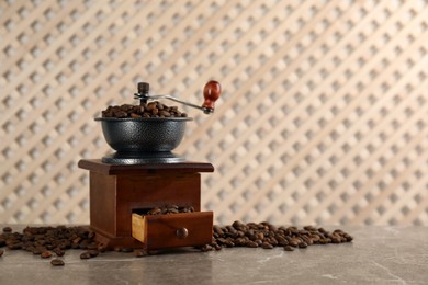 Vintage manual coffee grinder and beans on grey table. Space for text