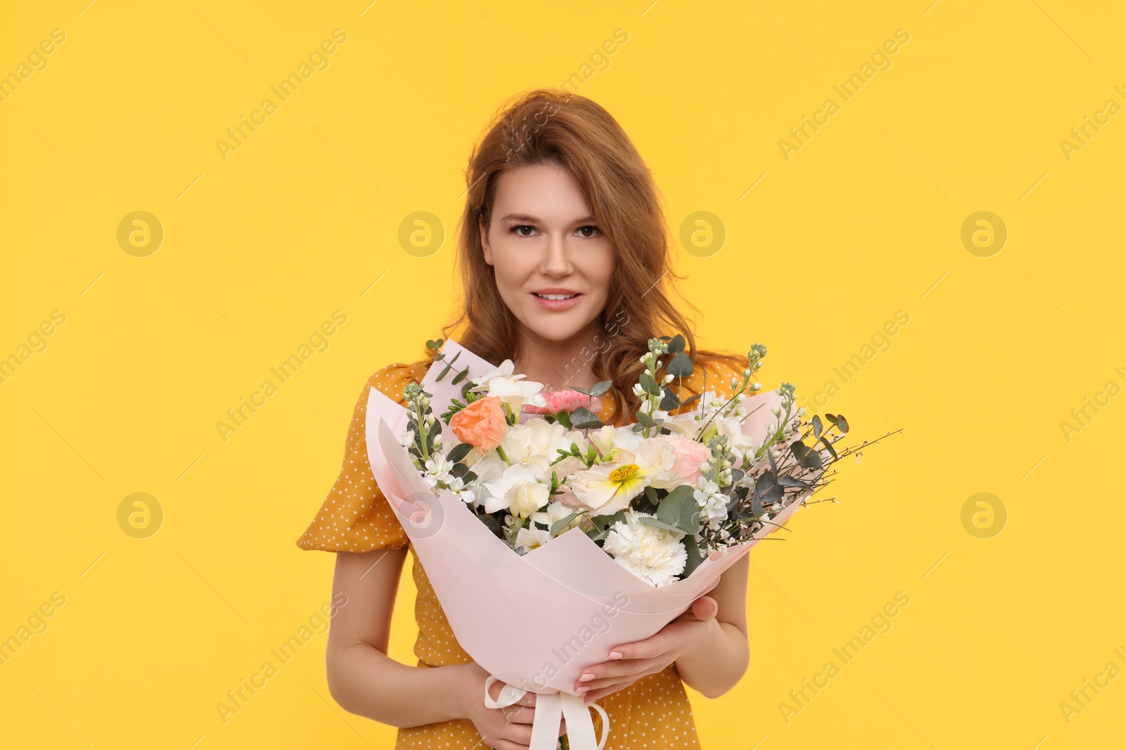 Photo of Happy woman with bouquet of beautiful flowers on yellow background