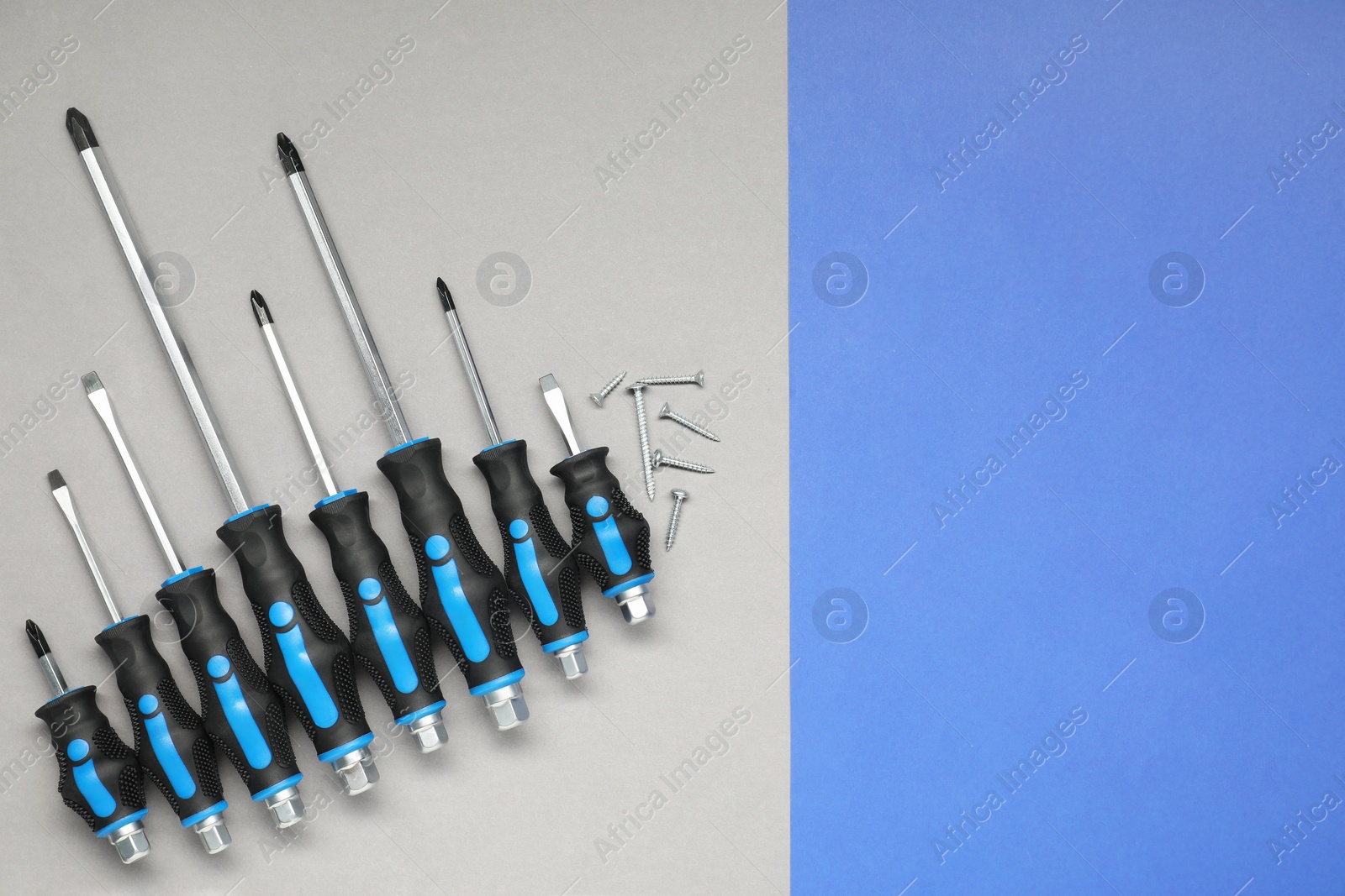 Photo of Set of screwdrivers and screws on color background, flat lay. Space for text