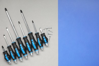Set of screwdrivers and screws on color background, flat lay. Space for text