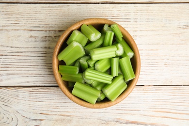 Photo of Cut celery in bowl on white wooden table, top view