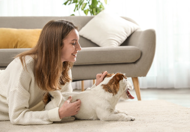 Photo of Young woman with her cute Jack Russell Terrier at home. Lovely pet