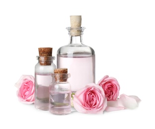 Bottles with rose essential oil and flowers on white background