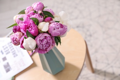 Photo of Vase with bouquet of beautiful peonies on table in room, space for text