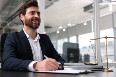 Photo of Smiling lawyer working at table in office. Space for text