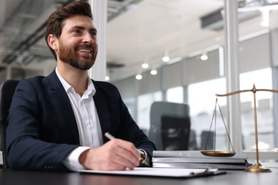 Smiling lawyer working at table in office. Space for text