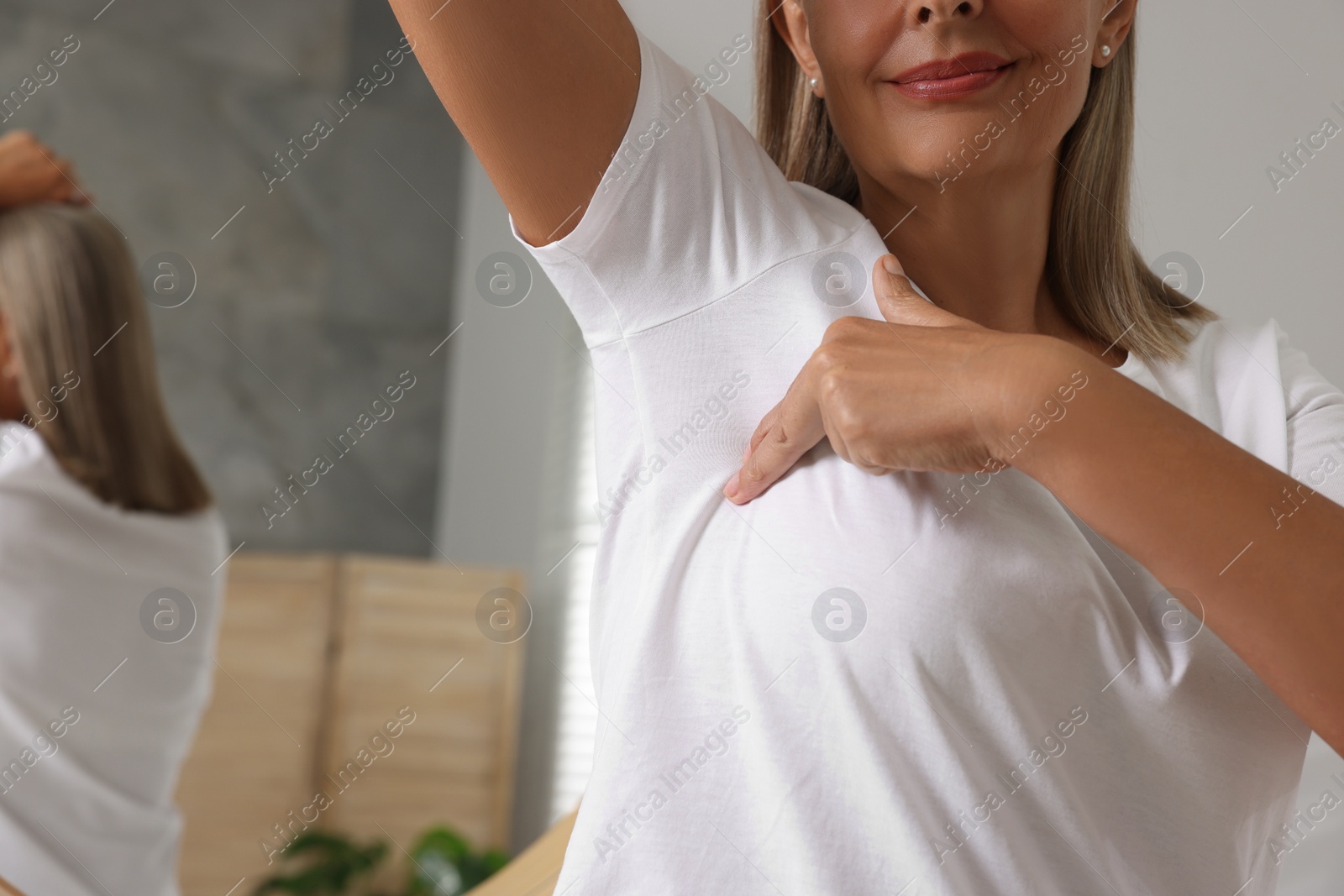 Photo of Woman doing breast self-examination in bathroom, closeup. Space for text