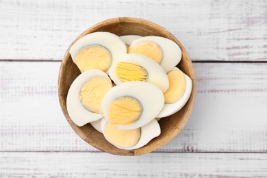 Bowl of fresh hard boiled eggs on white wooden table, top view