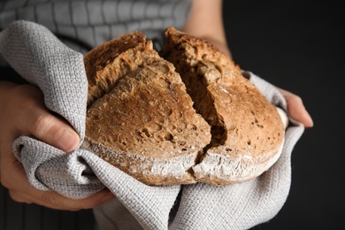 Photo of Woman holding tasty bread on dark background, closeup